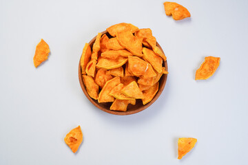 A bowl of papaya chips with a few pieces of food scattered around it