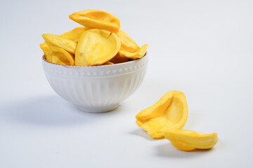 A bowl of yellow chips sits on a white table