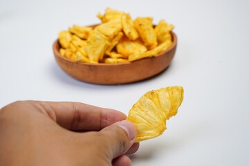 A person is holding a piece of pineapple in their hand
