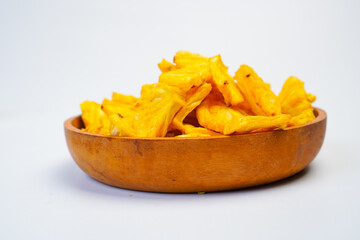 A bowl of yellow pineapple chips sits on a white background