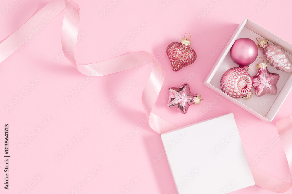 Wall mural Christmas holiday composition. Open gift box with satin ribbon and Christmas tree toys on pastel pink background. Christmas, winter, new year concept. Flat lay, top view, copy space