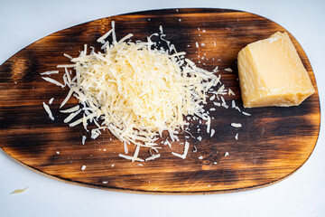 Grated Parmesan cheese and a piece on a wooden cutting board