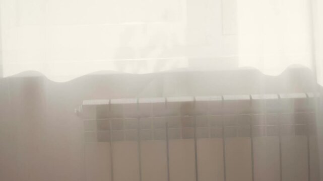 A white radiator thermostat for changing climatic conditions and temperature in a house, apartment, office, building against a white plastered wall