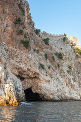 Alanya fortress on a cliff with a cave in summer under a blue cloudless sky