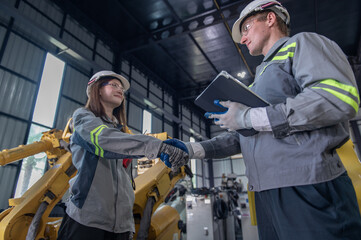 Engineer standing by robotic arm and operating machine in industry factory, technician worker check for repair maintenance electronic operation