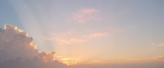 Fototapeta premium Radiant sunset with golden light and fluffy clouds in a soft pastel sky