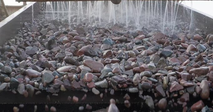 Close-up rocks move through vibrating screen. Crushing screening plant. Screening and washing in open-pit mining. Mining conveyor belt sorting rocks