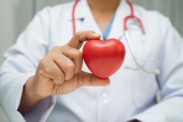 Asian woman doctor holding red heart for health in hospital.