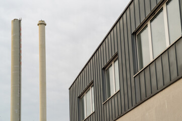 Modern office building standing near industrial smokestacks