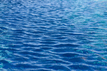 Gentle ripples dance on the surface of a crystal-clear blue pool under the warm afternoon sun