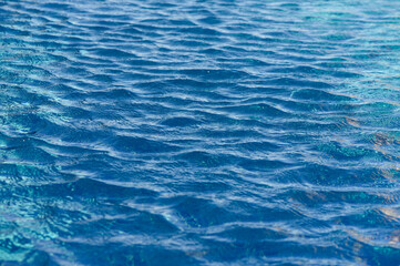 Rippling azure waves create a serene atmosphere on a sunny day at the tranquil poolside retreat