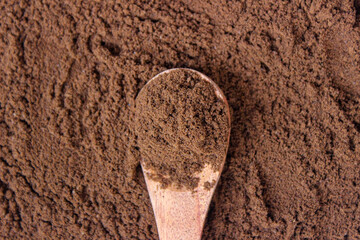 Roasted coffee powder on wooden spoon with coffee powder background, food background. closeup.
