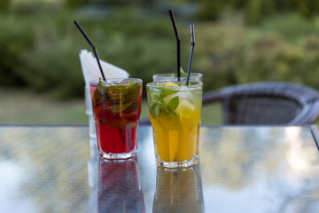 Two drinks on a table, one is a red drink and the other is a yellow drink