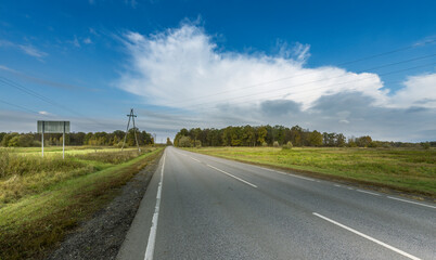 A road with a few trees in the background and a sign on the side
