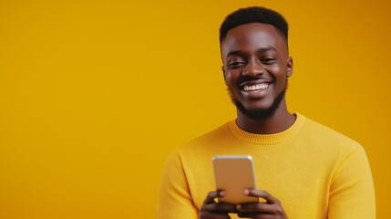 young smiling guy using mobile phone against yellow background