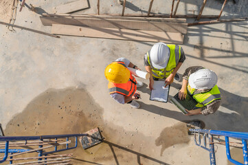 Three Asian engineers working at site of a large building project,Work overtime at construction site,Team of engineer discus at site,The architect, supervisor, and foreman meet to discuss the design