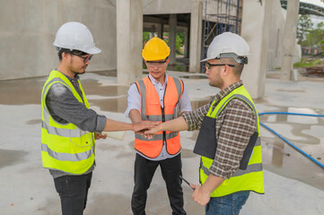 Three Asian engineers working at site of a large building project,Work overtime at construction site,Team of engineer discus at site,The architect, supervisor, and foreman meet to discuss the design