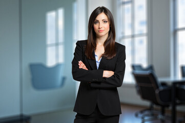 Confident businesswoman standing with arms crossed in office
