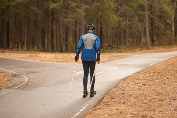 A man roller skis in an autumn park. Doing sports outside.