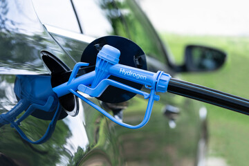 Close up of fuel cell car with connected hydrogen fueling nozzle.