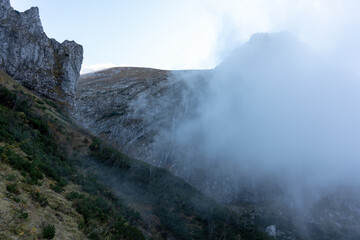 Misty mountain landscape with towering cliffs and low-lying clouds on a serene autumn morning. Concept of wilderness, nature's beauty, and calm mountain atmospheres. High quality photo