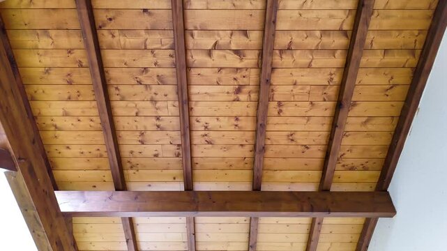 GROS PLAN SOUS TOITURE EN BOIS AVEC CHARPENTE VISIBLE, TOIT DOUBLE PANS AU-DESSOUS DE TOIT EN PIN VERNIS SOUS UN CIEL BLEU 