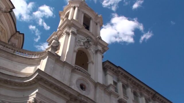 Piazza Navona: camera segue il movimento delle bolle di sapone, da sinistra a destra, inquadrando cupola di Sant'Agnese, obelisco e Fontana dei Quattro Fiumi, con un uomo di spalle