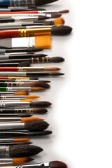 Fototapeta premium Mix of paint brushes in a row isolated on a white background. Top view.