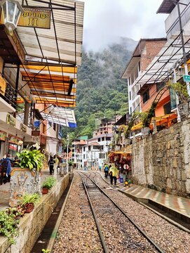 Vista de las calles de Aguas Calientes, Per&uacute;, con rieles de tren y edificios rodeados de vegetaci&oacute;n y monta&ntilde;as
