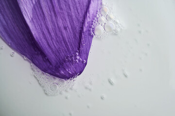 A drop of serum on a purple flower petal.