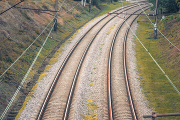 A beautifully scenic view showcasing curved railway tracks that are neatly lined with gravel, which are beautifully surrounded by lush greenery, all set within a vibrant urban environment