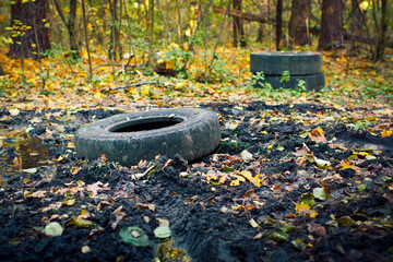 Old used car tires left in the forest. Environmental conservation concept. Toxic waste disposal...