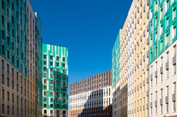 Obraz premium Colorful modern residential buildings with vibrant facades under a clear blue sky in urban areas