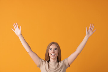 Lifestyle concept. A smiling beautiful woman with raised hands against an orange backdrop