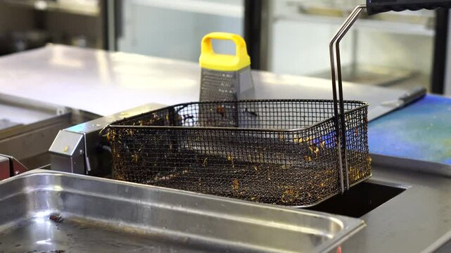 Dirty grid for french fries for deep frying in industry in the large kitchen of the hot workshop. The concept of fast food, delicious food, restaurant