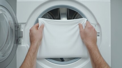 Person folding a blank white t-shirt in a laundry room, symbolizing minimalism and clean, everyday fashion