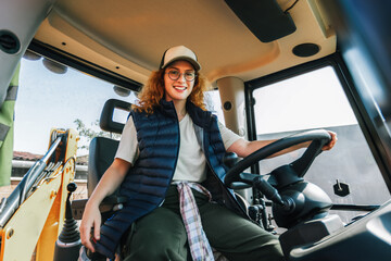Young ginger woman drives an excavator.