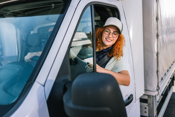 Portrait of professional woman truck driver looking out the window. People and industrial transportation concept.