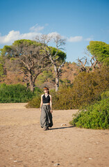 Redhead woman walking confidently through a sunny forest landscape