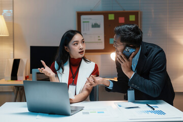 Two business partners working late in office, having an argument while one is having a phone call