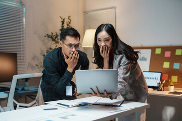 Two business colleagues looking surprised and worried while working late at the office