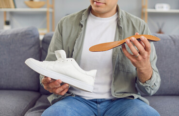 Close up of an orthopedist man inserting an insole into a shoe. Medical procedure related to...