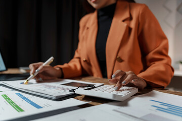 Businesswoman is calculating expenses and analyzing financial charts at her desk