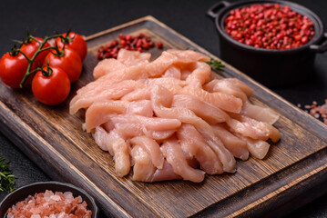 Raw chicken fillet cut into strips with spices and herbs