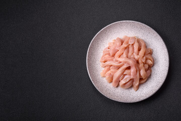 Raw chicken fillet cut into strips with spices and herbs