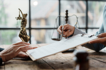 Lawyer is pointing at a document with a pen, discussing details of a contract with a client in...