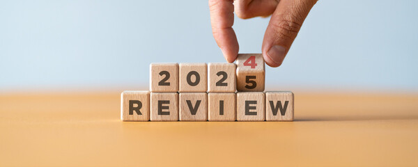Hand flipping of 2024 to 2025 on wooden blocks. 2024 business and customer review for business...