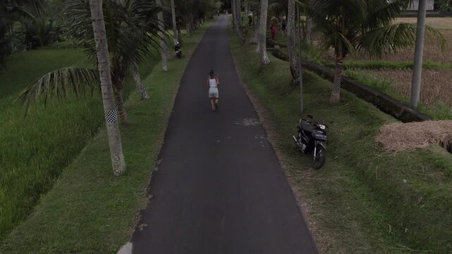 Persona corriendo en una carretera entre palmeras y campos de arroz en Bali.