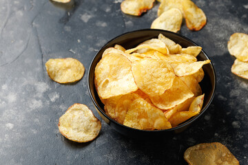 Crispy potato chips in black bowls. Snack food
