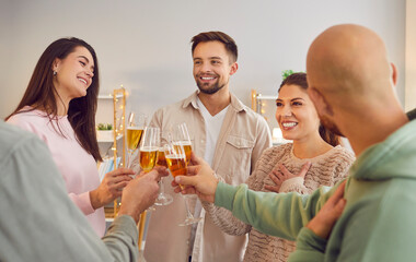 A group of handsome young people standing toasting with glasses of wine, close-up. Friends congratulate each other. A woman enjoys hearing a toast. Concept for home party, alcoholic weekend